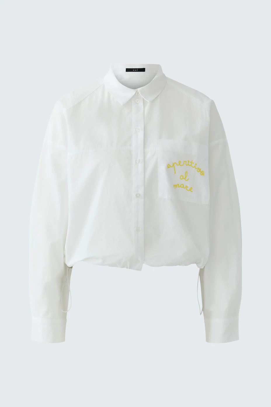 White shirt blouse with yellow text on pocket, featuring a classic collar and button-up front.
