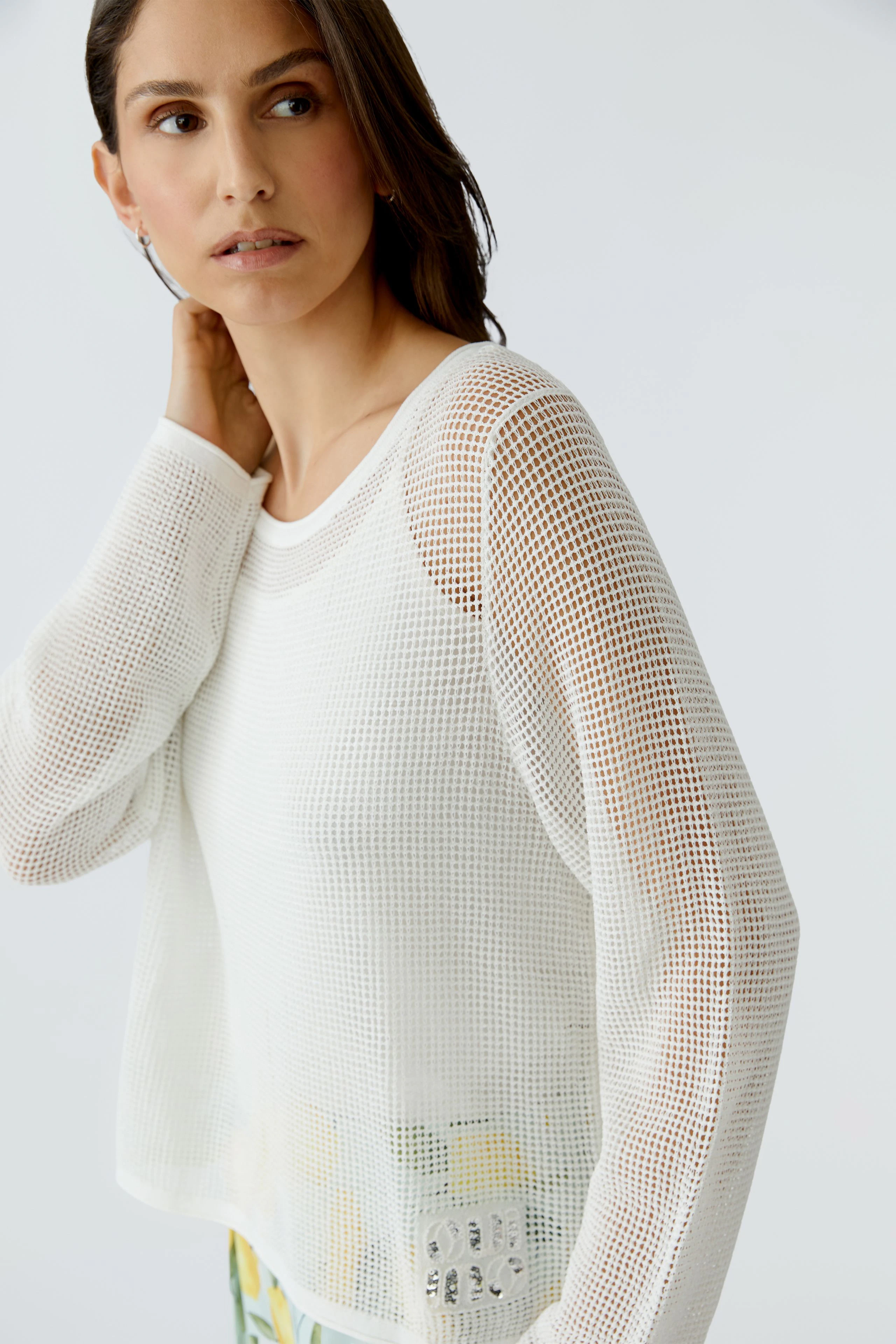Lässiger Damen-Pullover: Frau im weißen Netzpullover mit langen Ärmeln und modernem Look.
