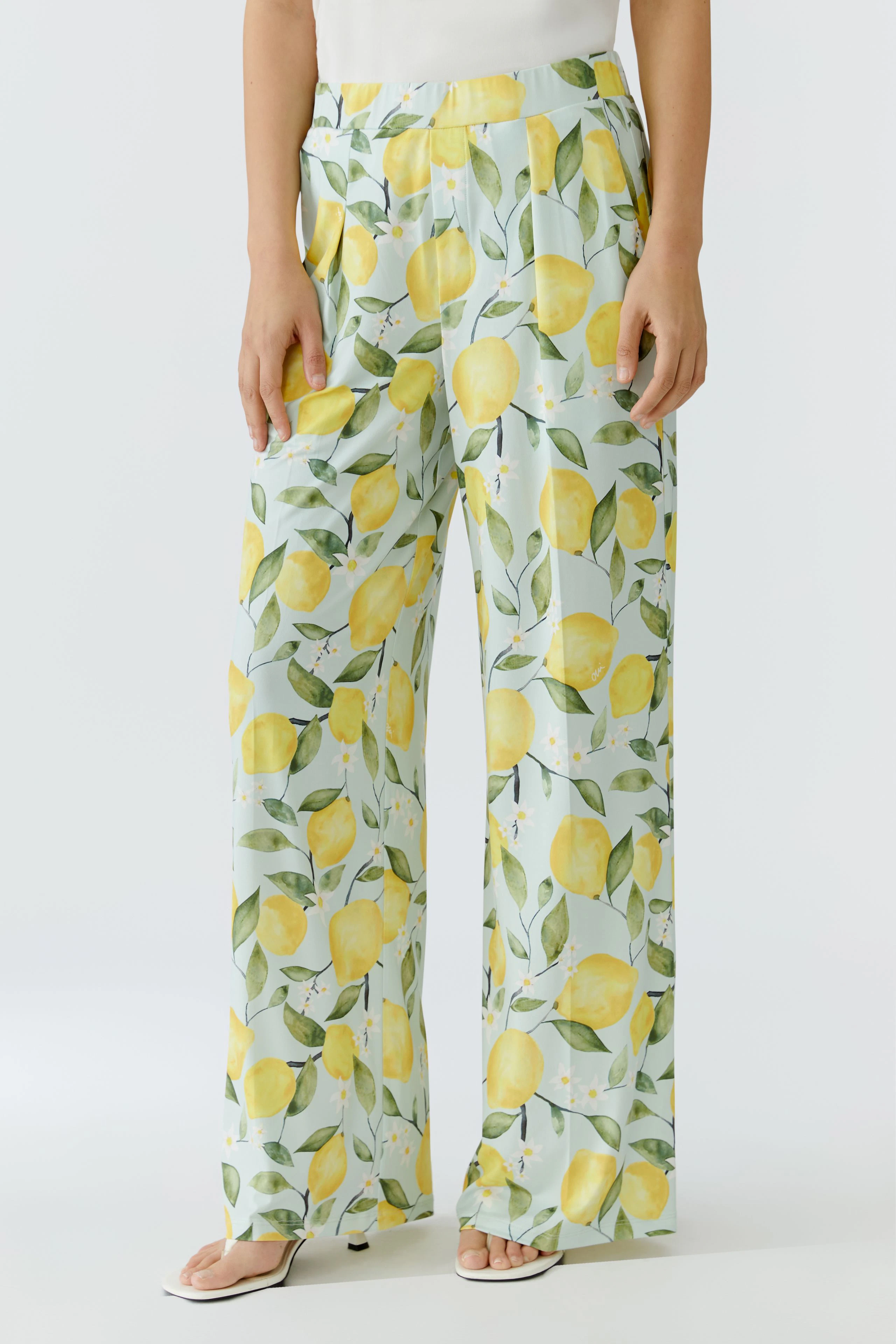 Woman in lemon-print pants, standing confidently. Bright, casual style with a fresh, summery vibe.