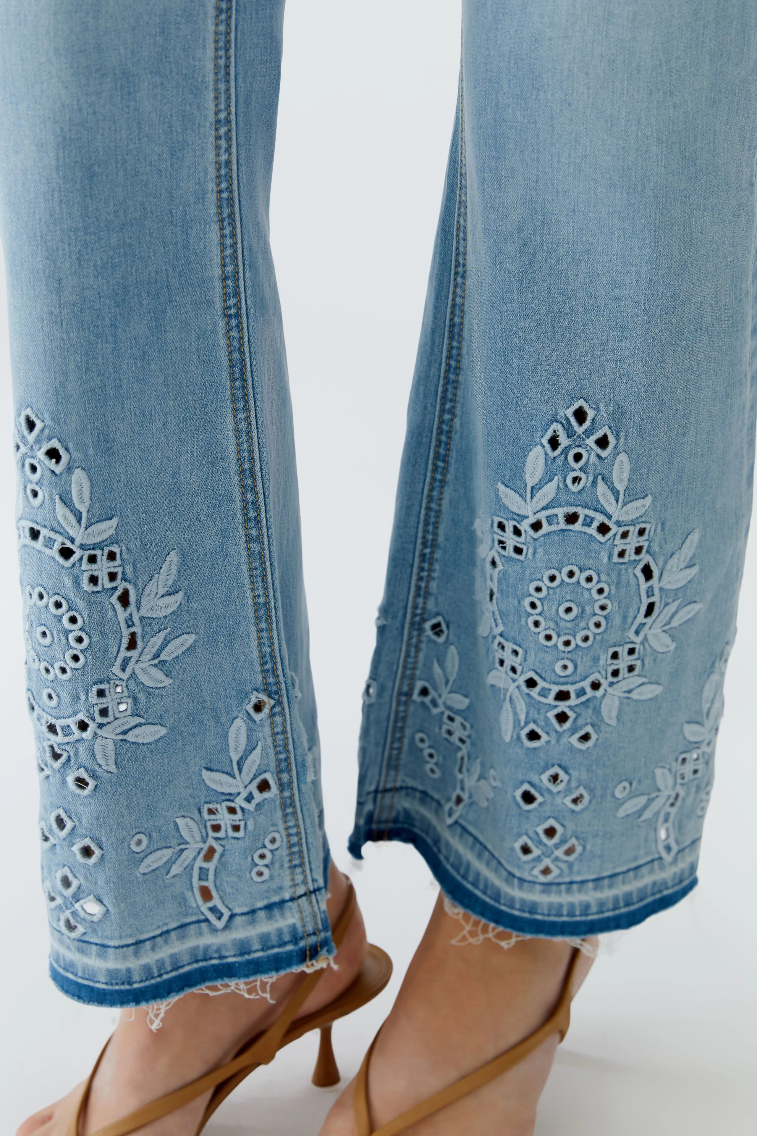 Jeans Bootcut: Detailansicht der Stickerei an den Hosenbeinen, getragen von einer Frau mit Sandalen.