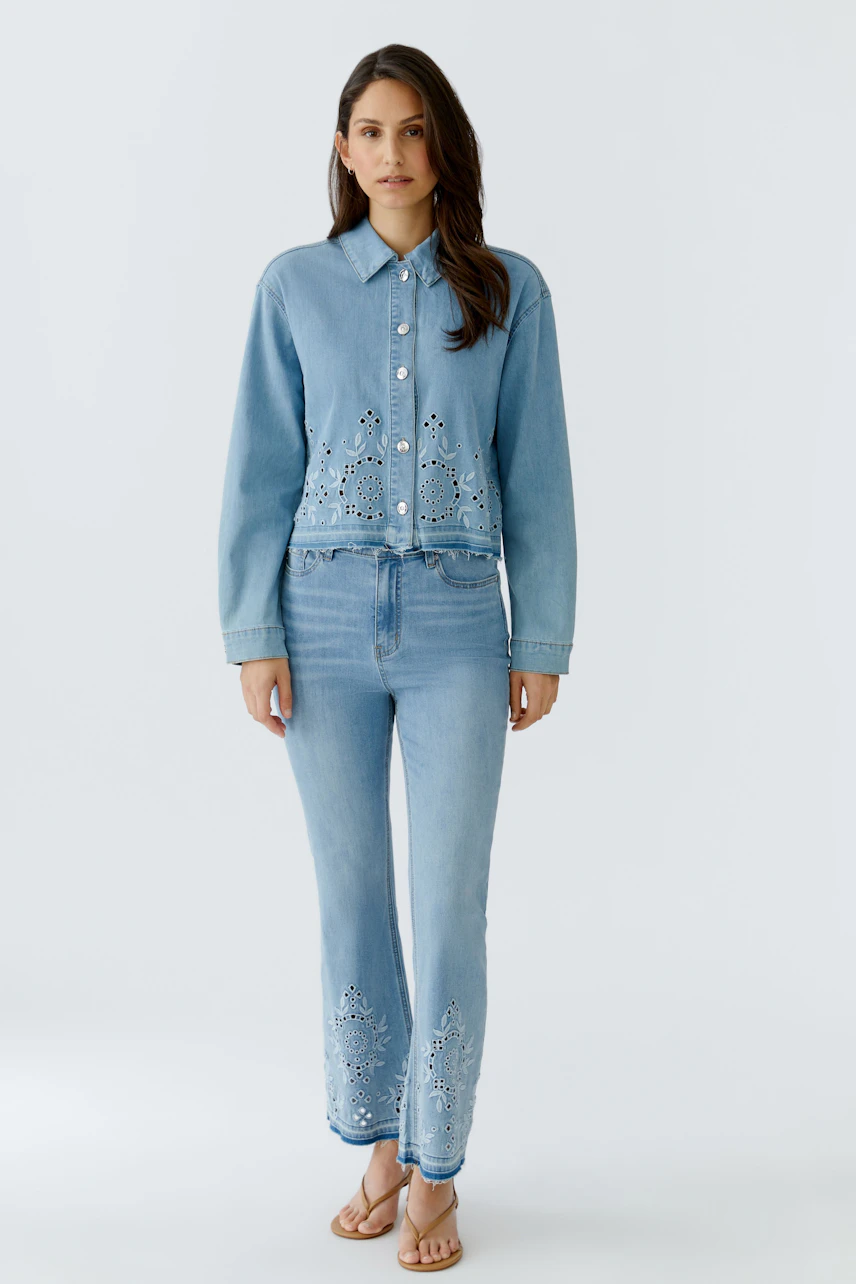 Frau in Jeans Bootcut: Hellblaue Jeans mit Stickerei, kombiniert mit passender Jacke, lässig und modern.