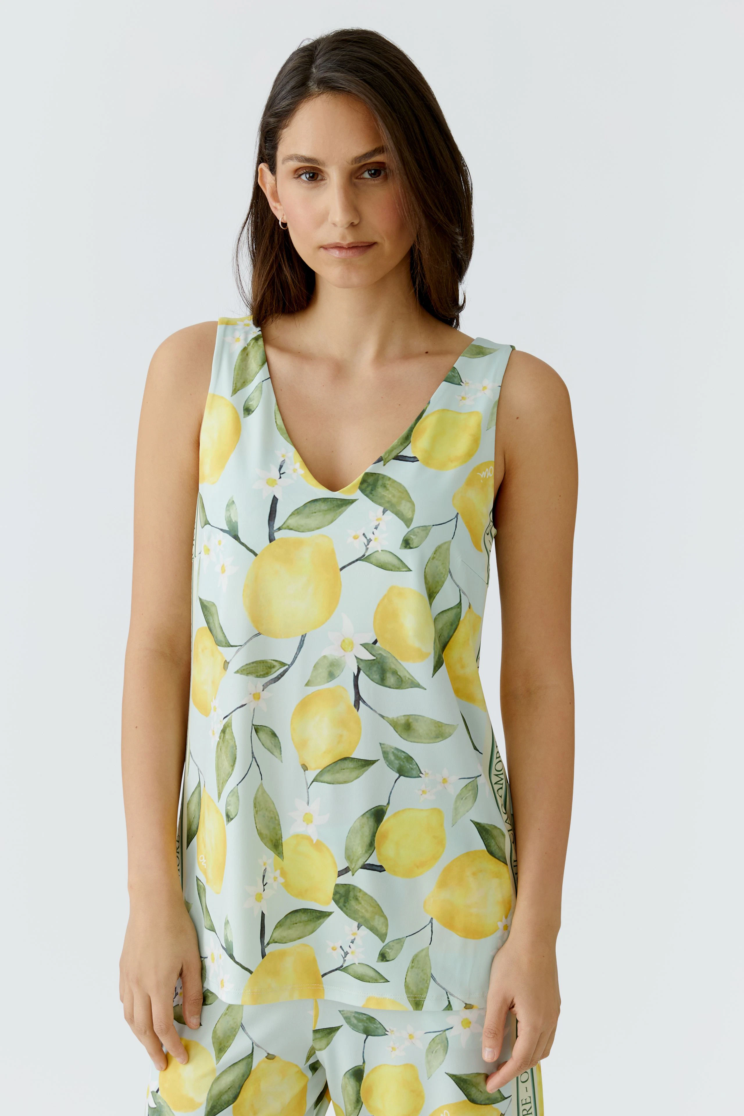 Woman in lemon-patterned top: Sleeveless, V-neck design with vibrant yellow lemons and green leaves.