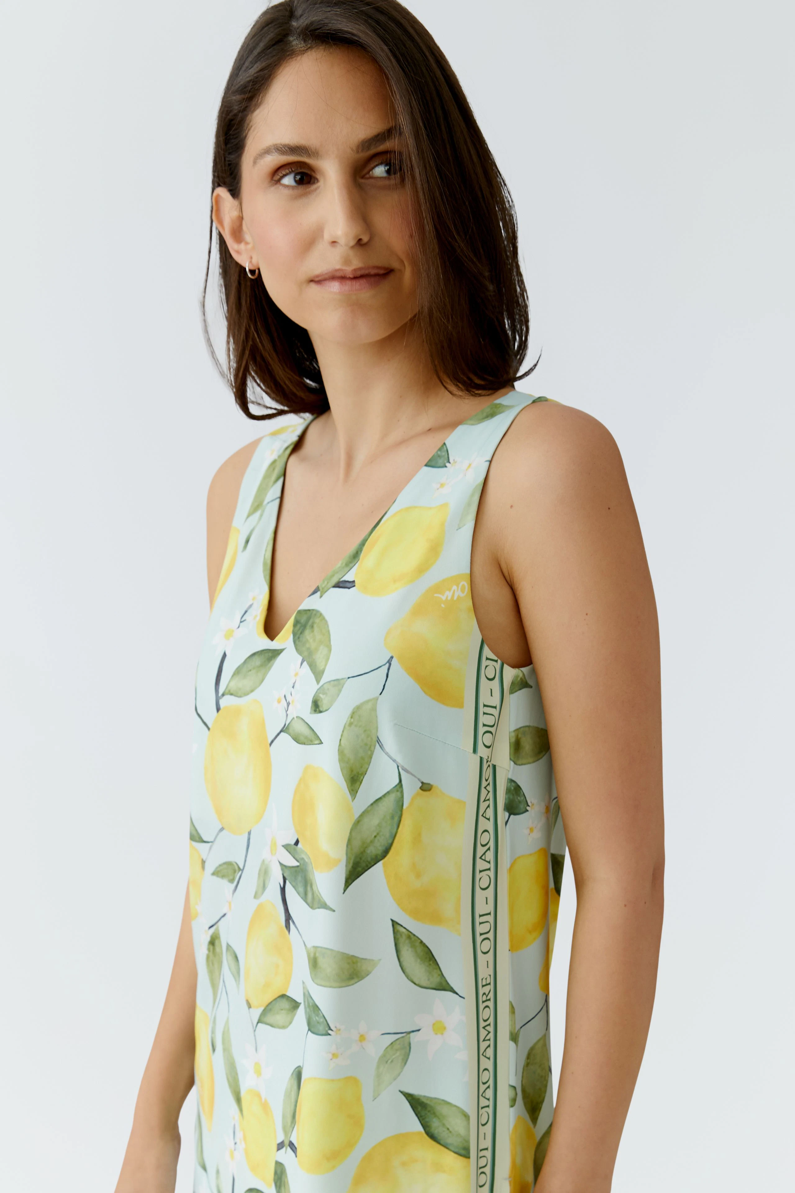 Woman in lemon-patterned top: Sleeveless, light fabric, perfect for summer.