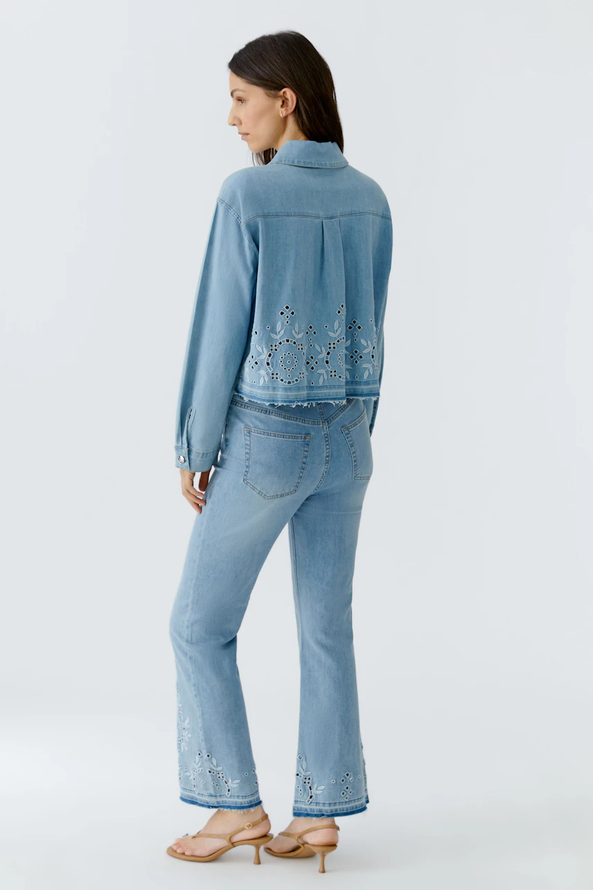 Casual denim jacket: Woman in light blue jeans jacket with delicate cut-out details, matching jeans.