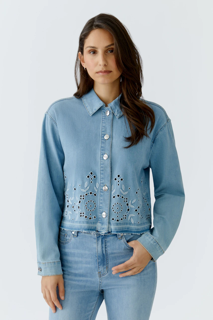 Casual denim jacket: Woman in light blue jeans jacket with floral cutouts, paired with matching jeans.