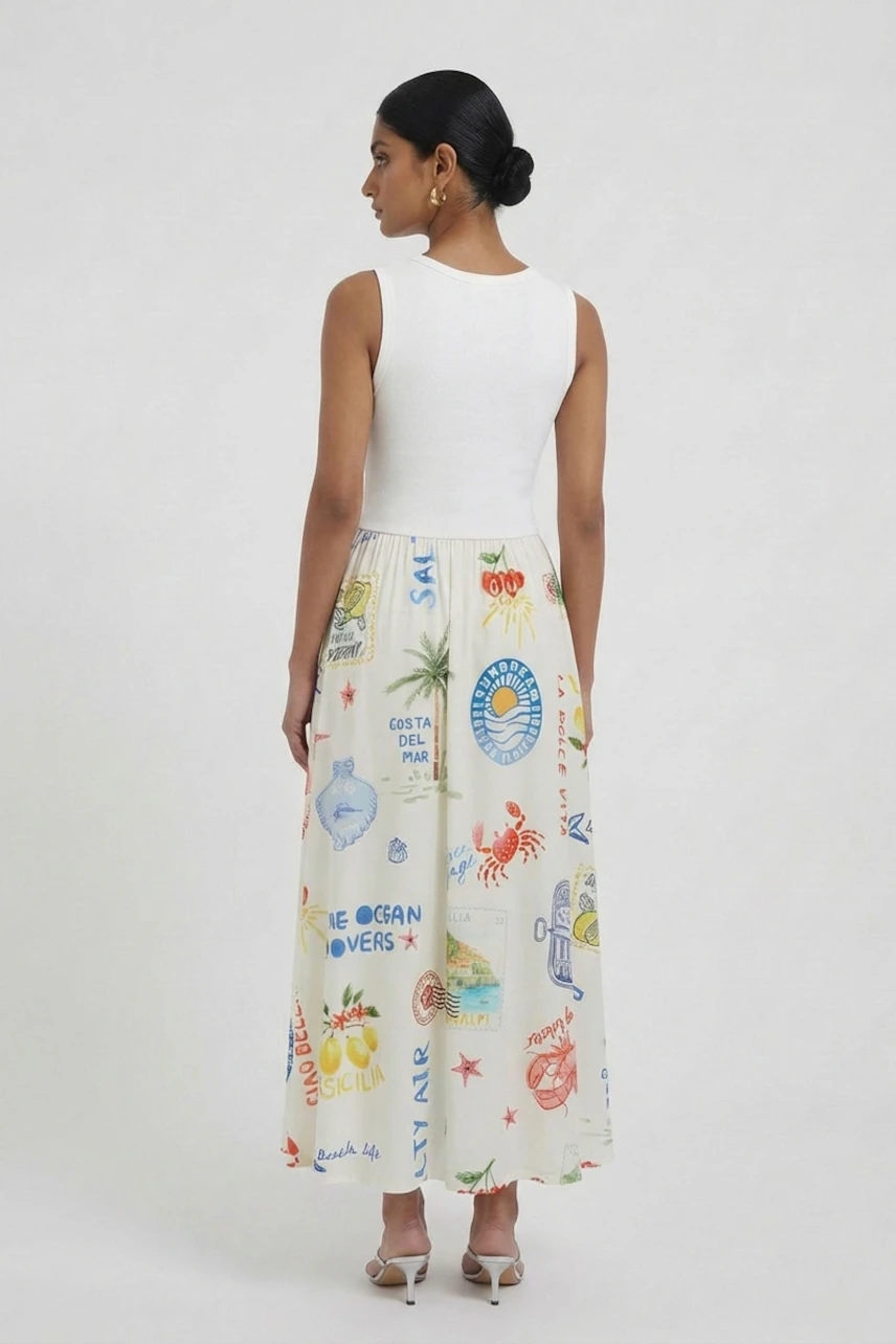 Woman in a sleeveless white top and colorful print midi dress, standing confidently in white heels.