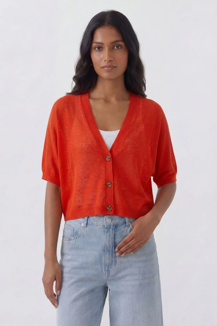 Casual cardigan: Woman in vibrant orange cardigan with button closure, paired with light blue jeans.