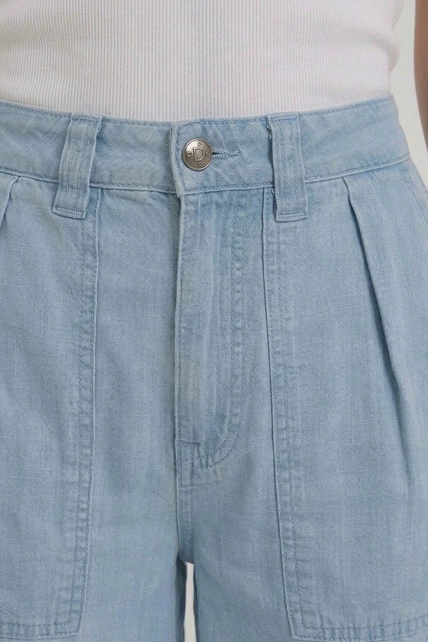 Casual wide leg jeans in light blue denim, featuring pleats and a high waist, worn by a woman.