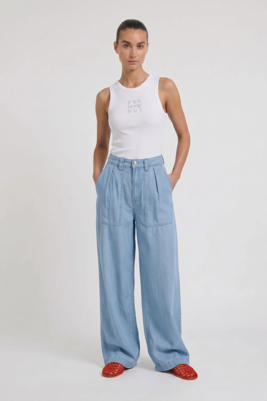 Casual wide leg jeans: Woman in light blue wide leg jeans, striped tank top, and red sandals.
