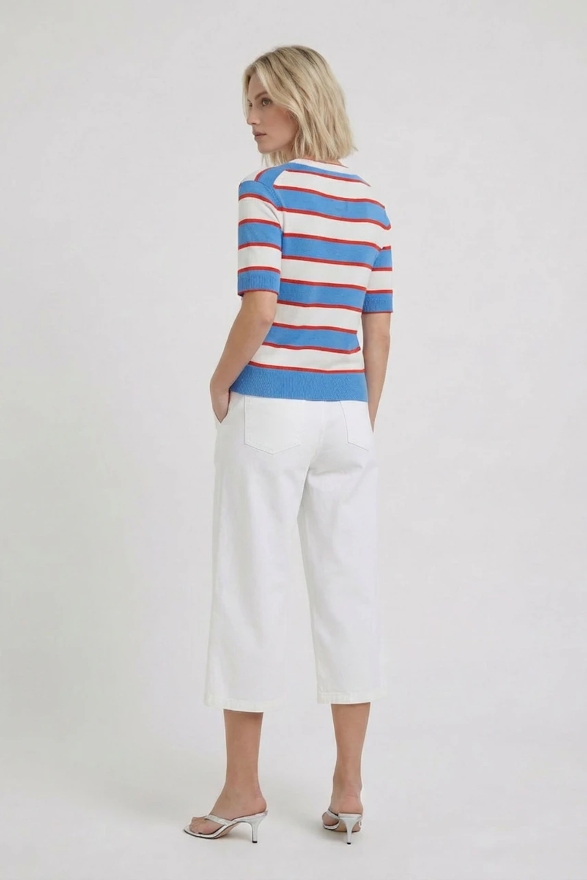 Casual women's pullover: Woman in a blue and red striped pullover with white pants, looking relaxed.