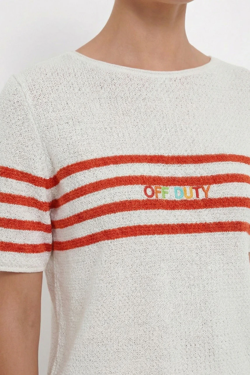 Damen-Pullover: Frau im weißen Pullover mit roten Streifen und "OFF DUTY" Schriftzug.