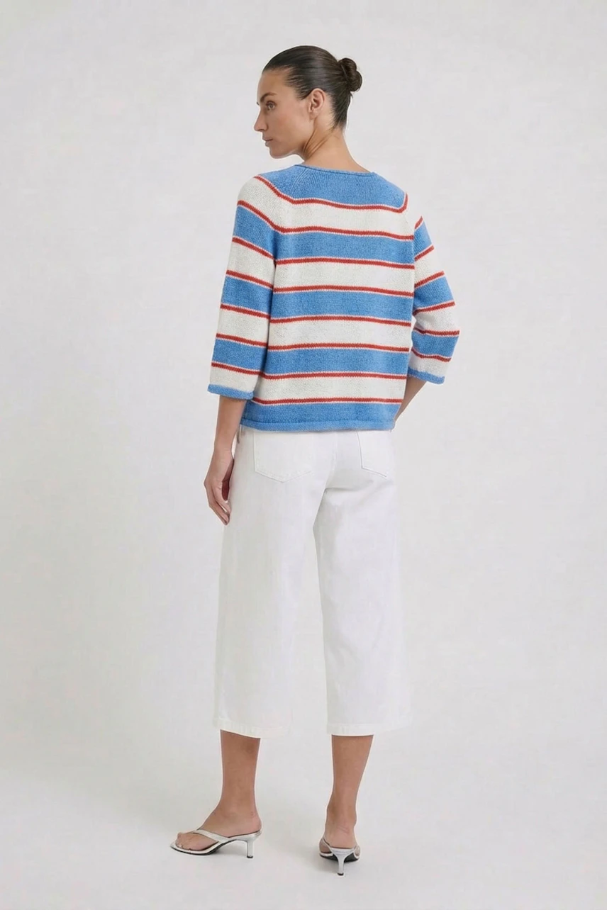 Casual pullover: Woman in a striped pullover with blue, red, and white colors, paired with white pants.