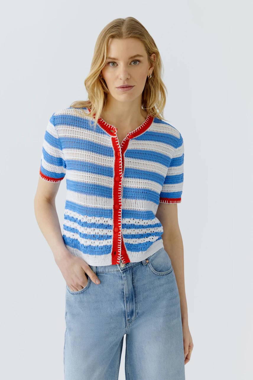 Casual cardigan: Woman in a striped blue and white cardigan with red accents, paired with light jeans.