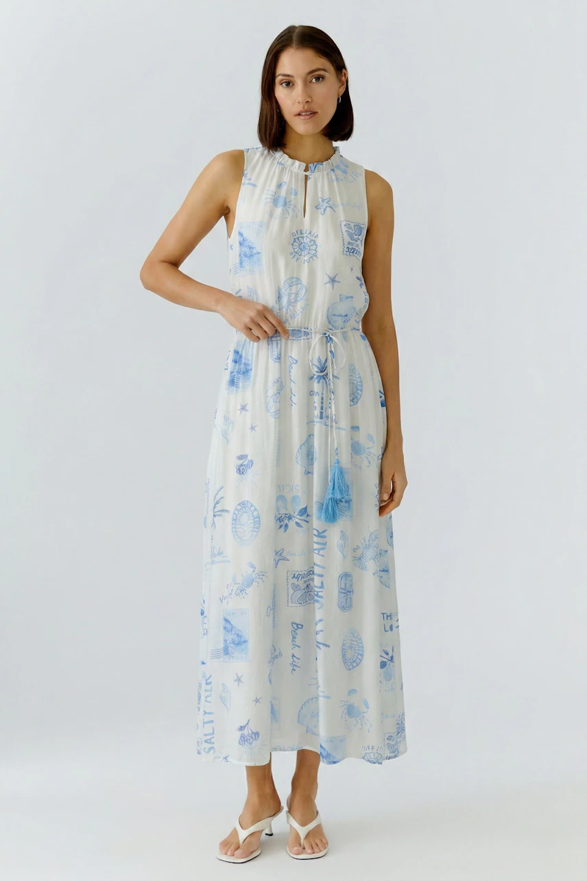Casual maxi dress: Woman in sleeveless, printed maxi dress with blue patterns, standing confidently.