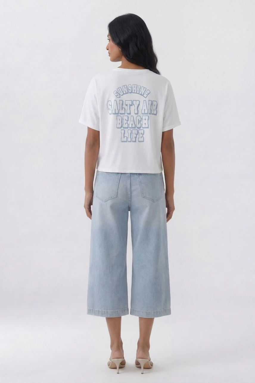 Casual T-shirt: Woman in white T-shirt with beach-themed print, paired with light blue wide-leg jeans.
