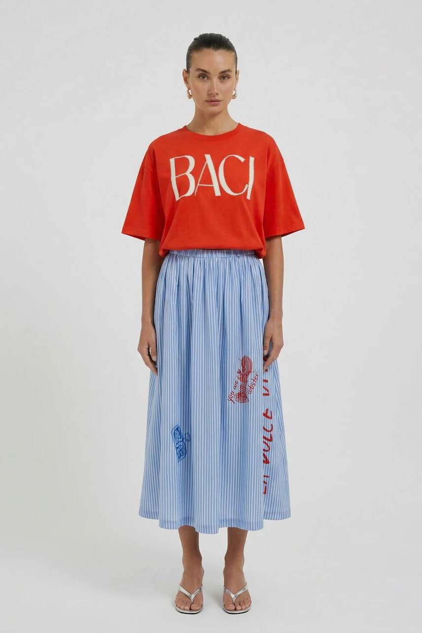 Casual T-shirt: Woman in red T-shirt with bold white letters, paired with a blue pleated skirt.