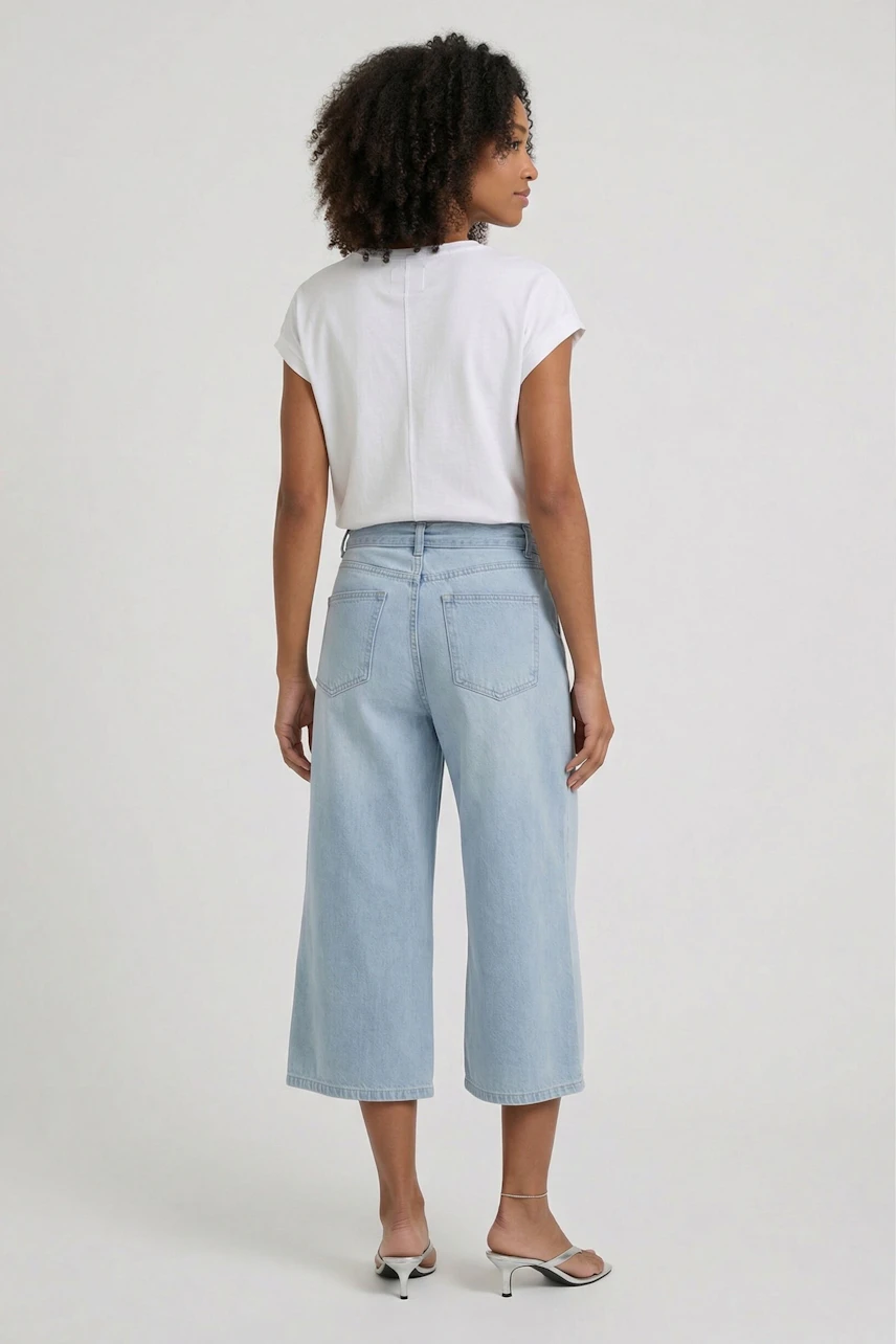 Casual women's T-shirt: Woman in white T-shirt and light blue jeans, viewed from the back.