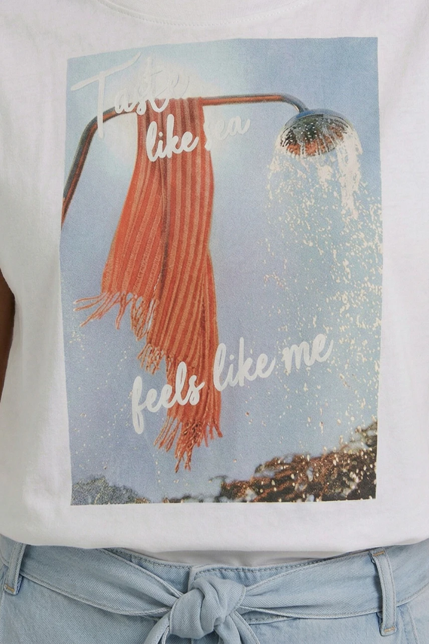 Casual T-shirt: Woman in white T-shirt with graphic print, paired with light blue jeans, exudes relaxed style.
