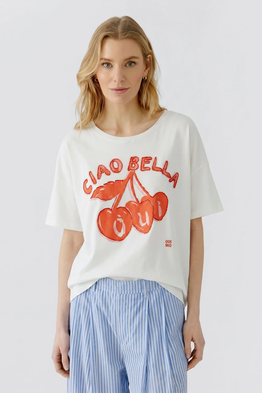 Lässiges Damen-T-Shirt: Frau im weißen T-Shirt mit rotem Print und blauer Jeans schaut direkt.