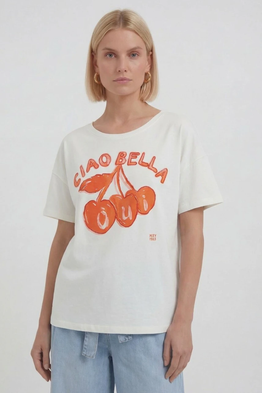Casual women's T-shirt: Woman in white tee with red cherry print and 'Ciao Bella' text, paired with jeans.