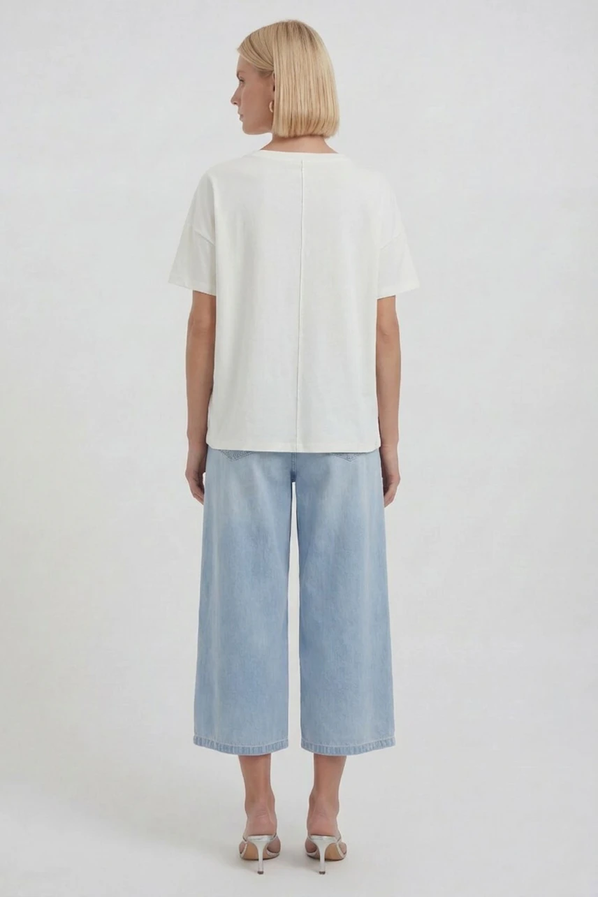 Casual women's T-shirt: Woman in a white T-shirt and light blue jeans, viewed from the back.