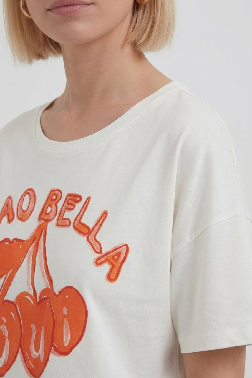 Casual women's T-shirt: Woman in white T-shirt with orange cherry print and "Ciao Bella" text.