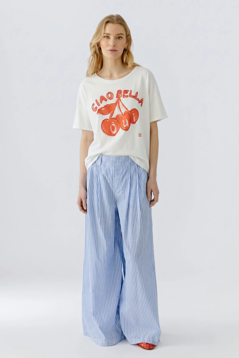 Weißes Damen-T-Shirt mit rotem Kirschen-Print und Schriftzug 'Ciao Bella'. Ideal für einen frischen Look.