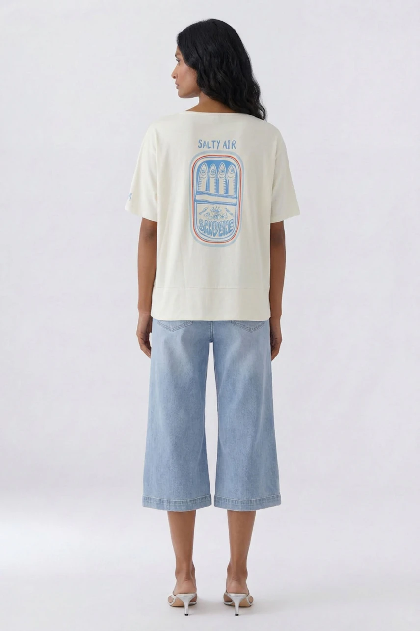 Casual T-shirt: Woman in a white T-shirt with graphic print, paired with light blue wide-leg jeans.