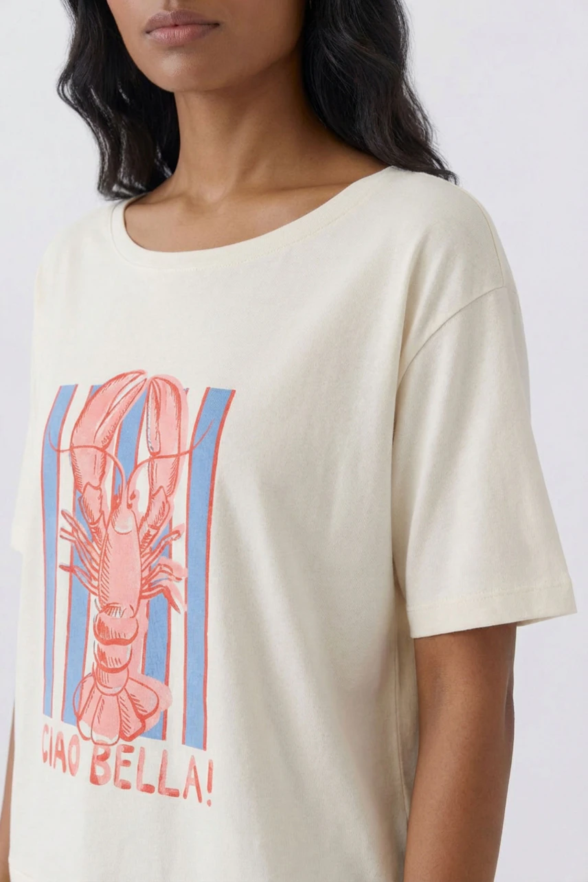 Casual women's T-shirt: Woman in cream T-shirt with lobster print and 'Ciao Bella!' text.