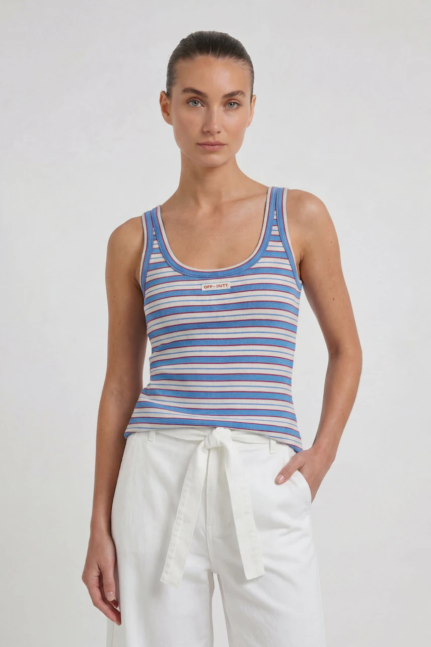 Striped tank top: Woman in a colorful striped tank top and white pants, standing confidently.
