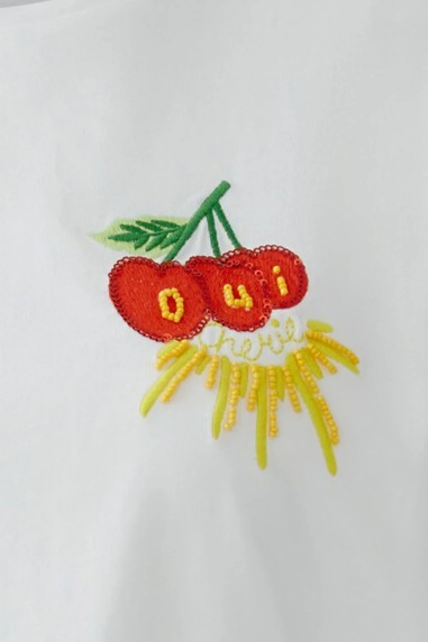 White T-shirt with cherry embroidery and 'Oui' text, showcasing a playful and vibrant design.