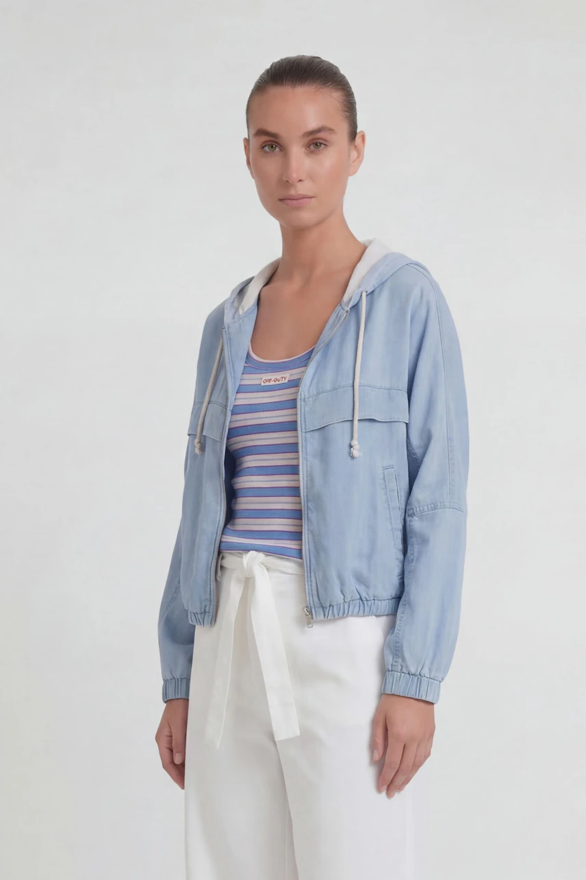 Casual women's jacket: Woman in light blue hooded jacket over striped top, paired with white pants.