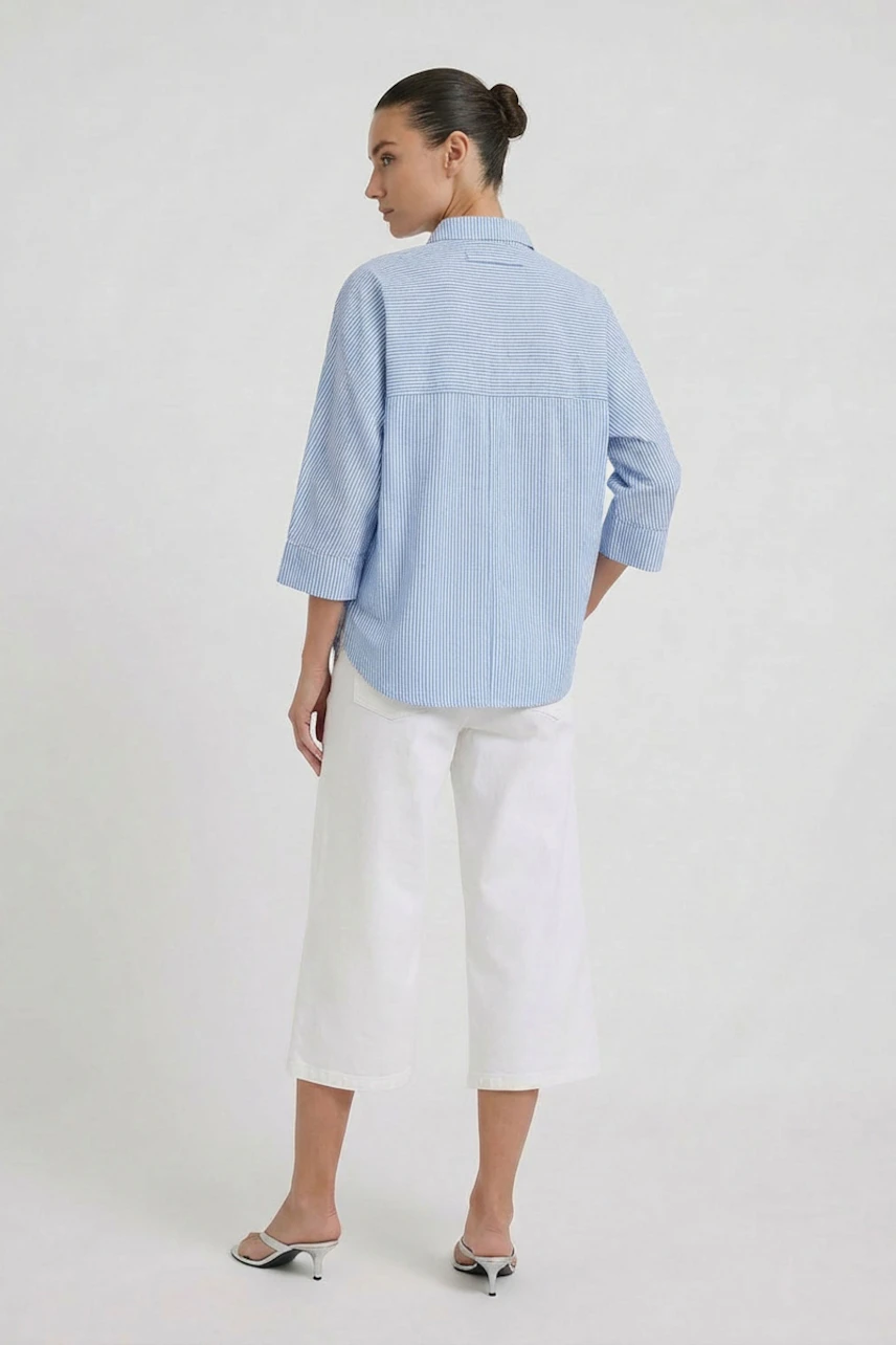 Casual blouse: Woman in light blue blouse with 3/4 sleeves, paired with white wide-leg pants.