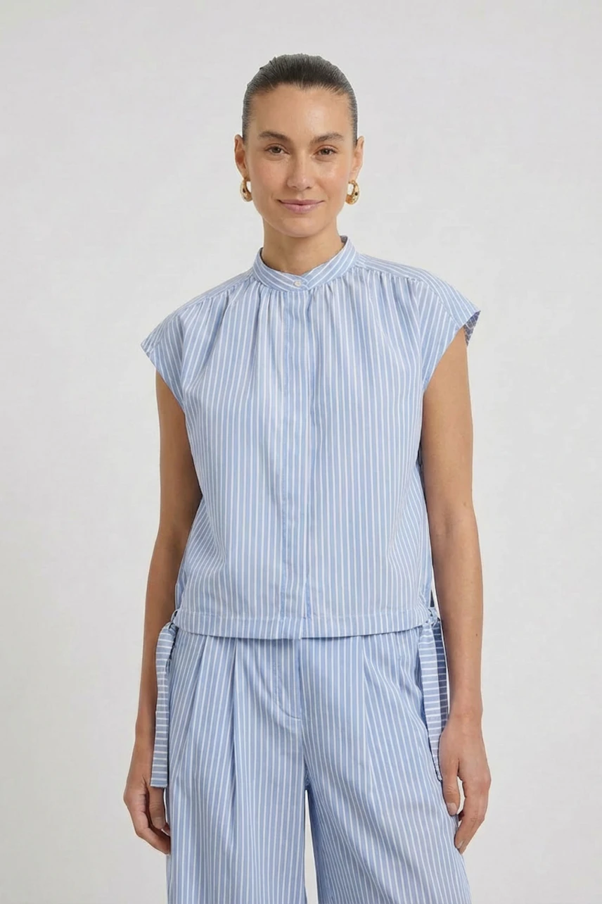 Striped blouse: Woman in a blue and white striped blouse with cap sleeves, smiling confidently.
