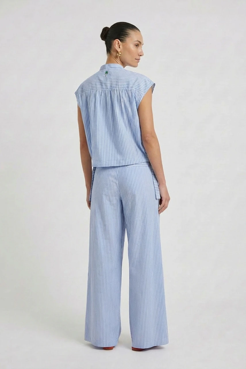 Casual women's blouse: Woman in a blue striped blouse with matching wide-leg pants, looking away.