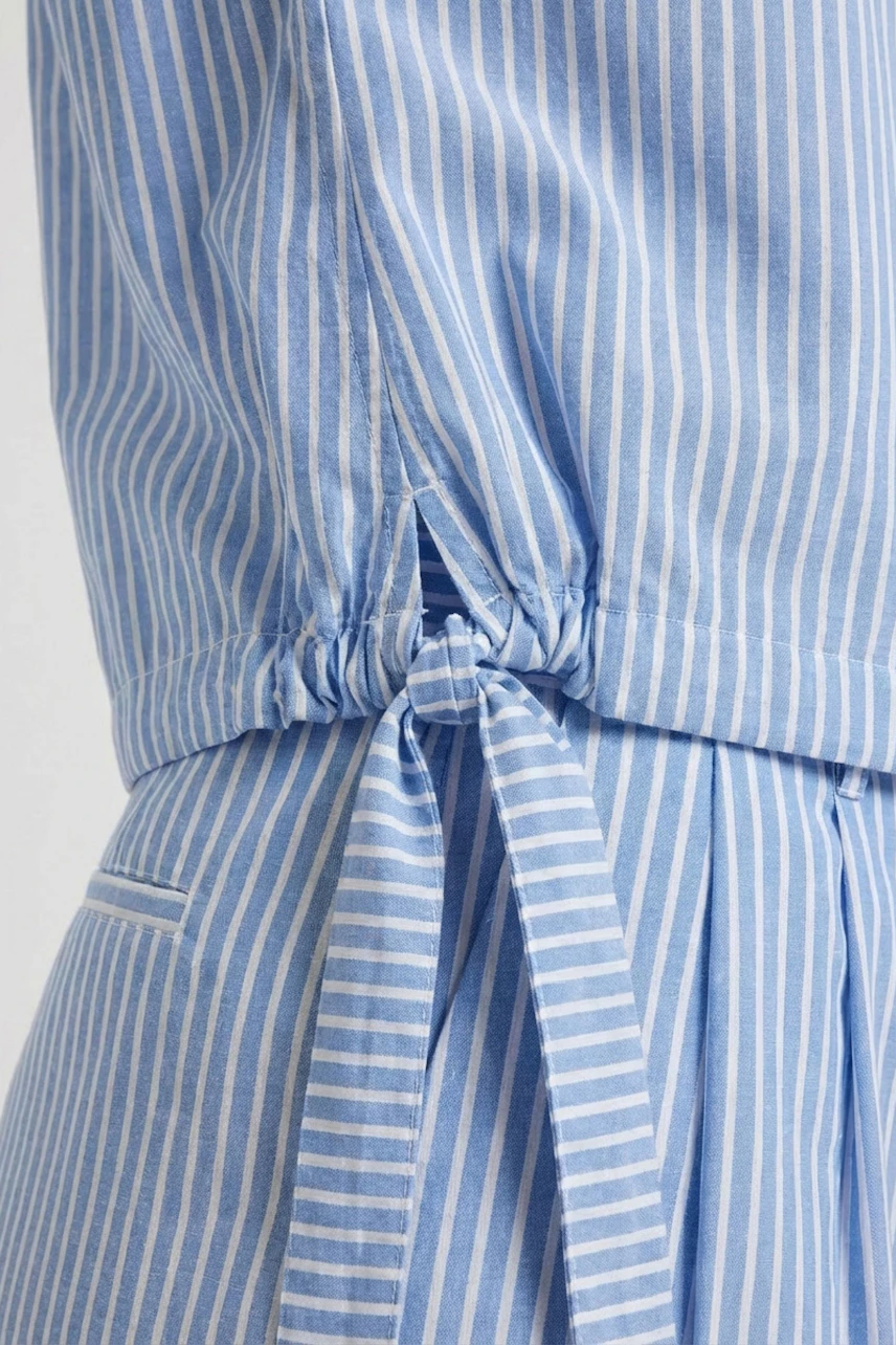 Striped blouse with tie detail: Close-up of blue and white striped fabric with waist tie, no model visible.