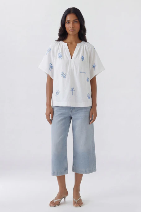 Weiße Damen-Bluse mit blauem Muster, locker geschnitten, ohne Model abgebildet.