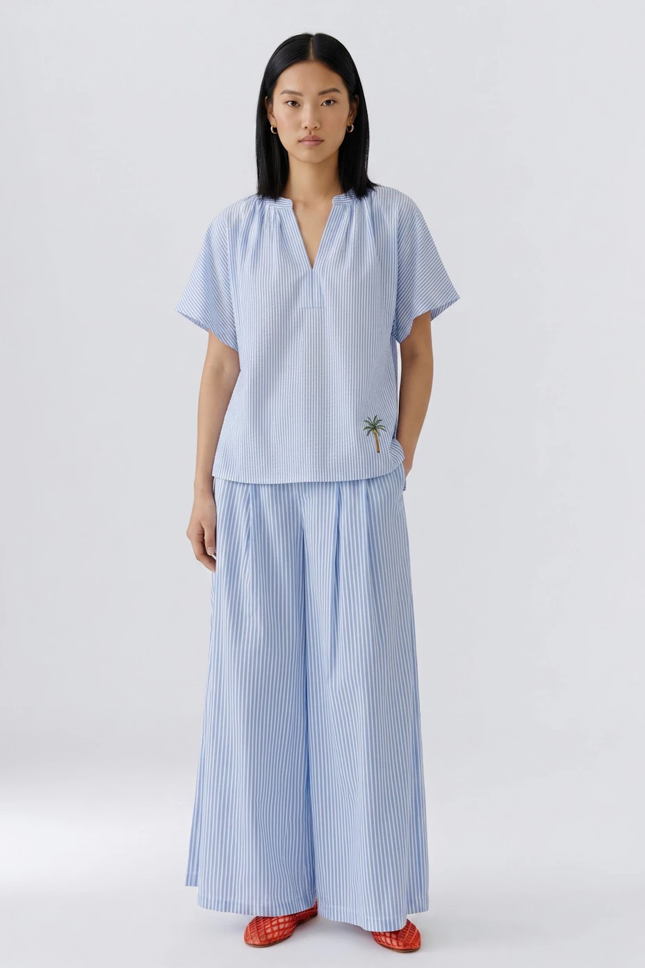 Casual women's blouse: Light blue blouse with short sleeves and palm tree embroidery.