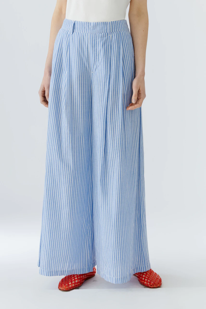 Woman in blue striped Marlene pants, white top, and red shoes. Casual and stylish look.