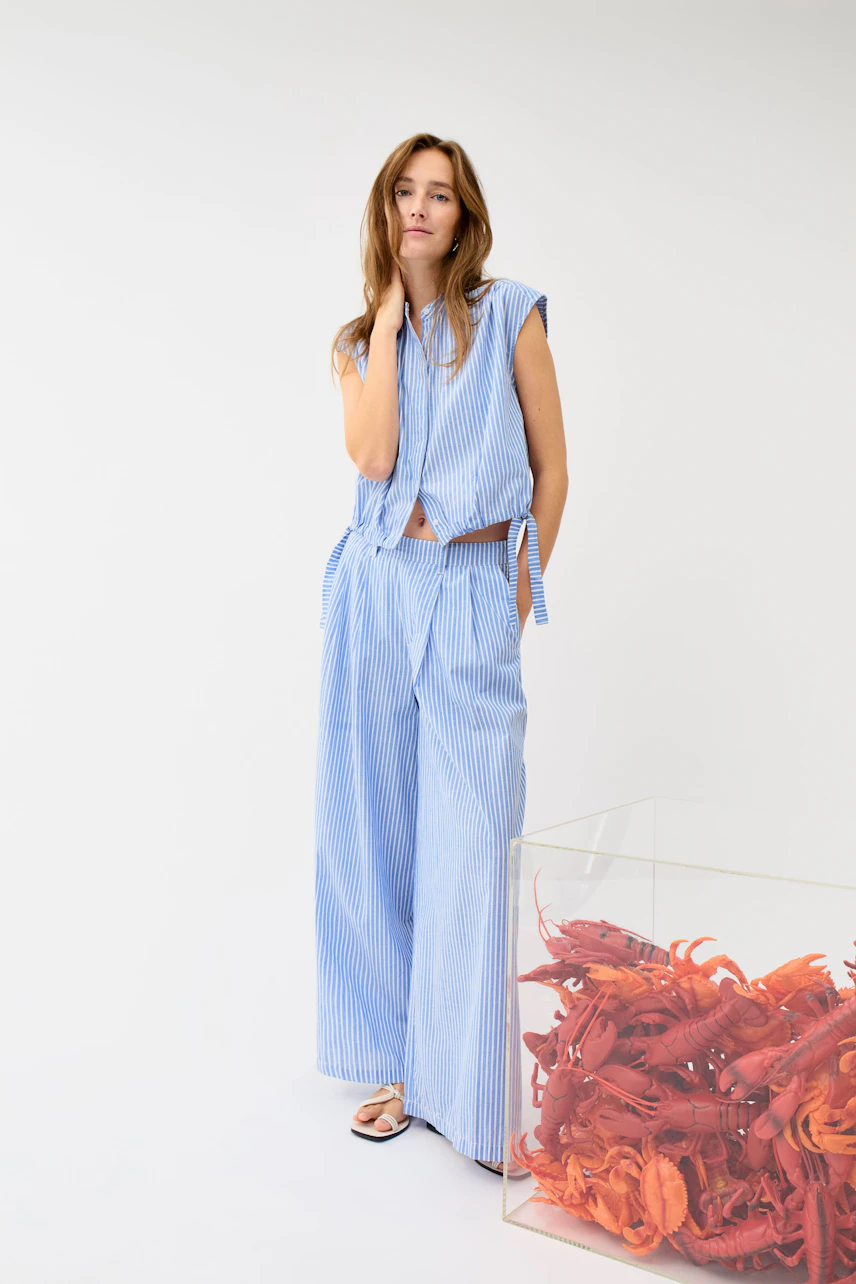 Casual Marlene trousers: Woman in blue striped Marlene trousers and matching top, standing confidently.