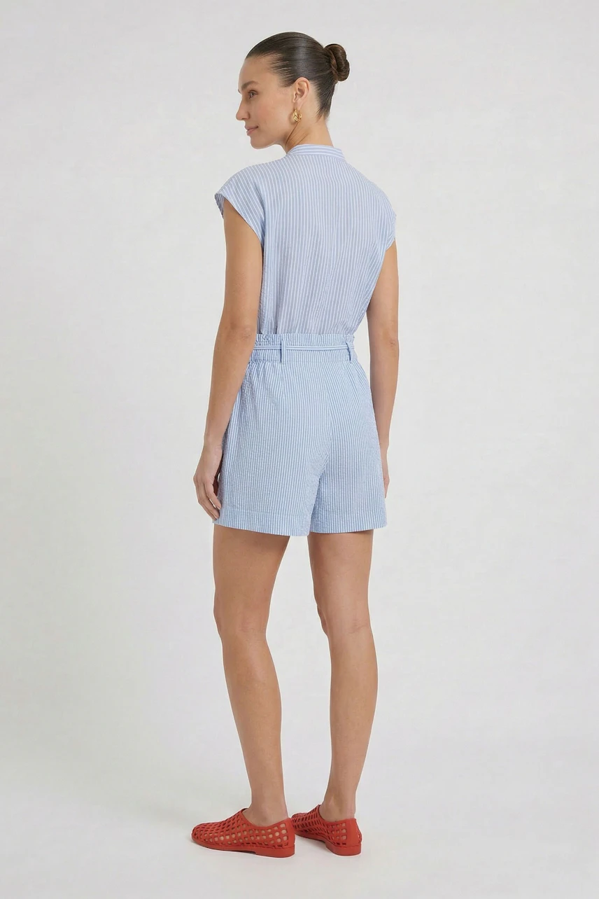 Casual women's shorts: Woman in light blue shorts with a matching top and red shoes, standing confidently.