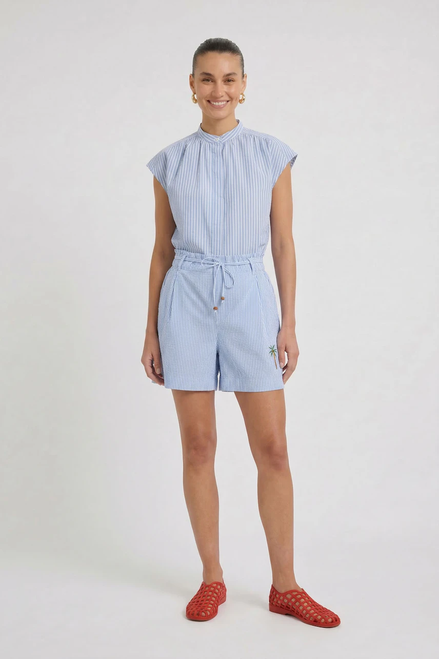Casual women's shorts: Woman in light blue striped shorts and top, smiling confidently.