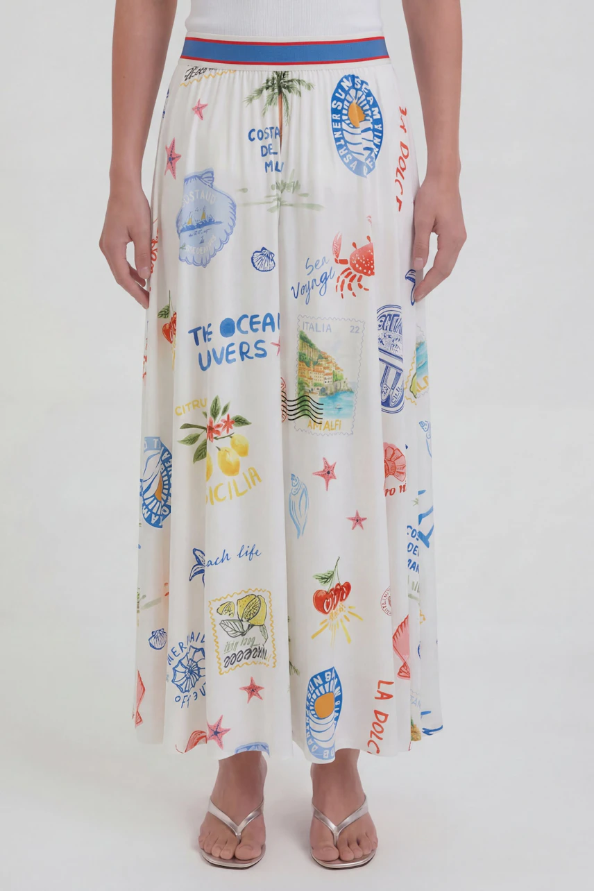 Colorful maxi skirt: Woman in a vibrant printed maxi skirt with beach motifs, standing in sandals.