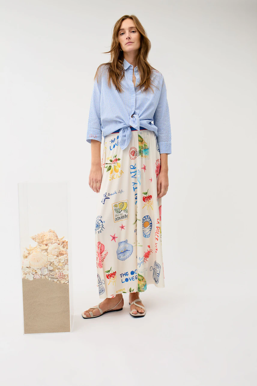Casual maxiskirt: Woman in a colorful print maxiskirt and blue shirt, standing confidently.