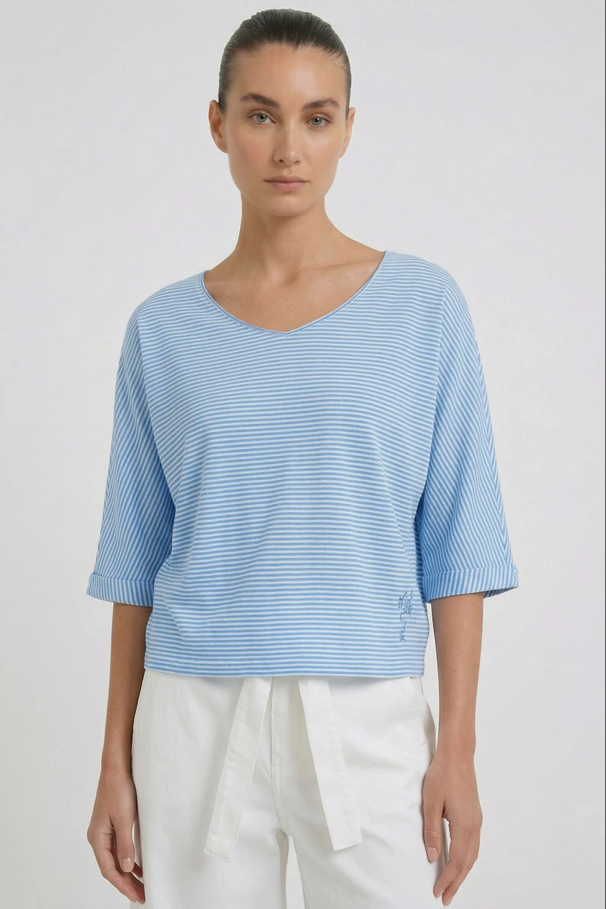 Casual women's T-shirt: Woman in a blue striped T-shirt with white pants, looking relaxed.