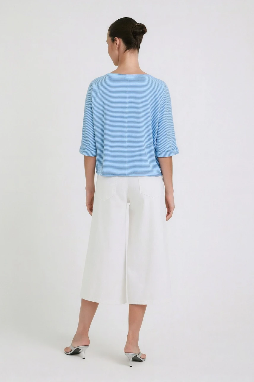 Casual women's T-shirt: Woman in a blue striped T-shirt and white culottes, viewed from the back.