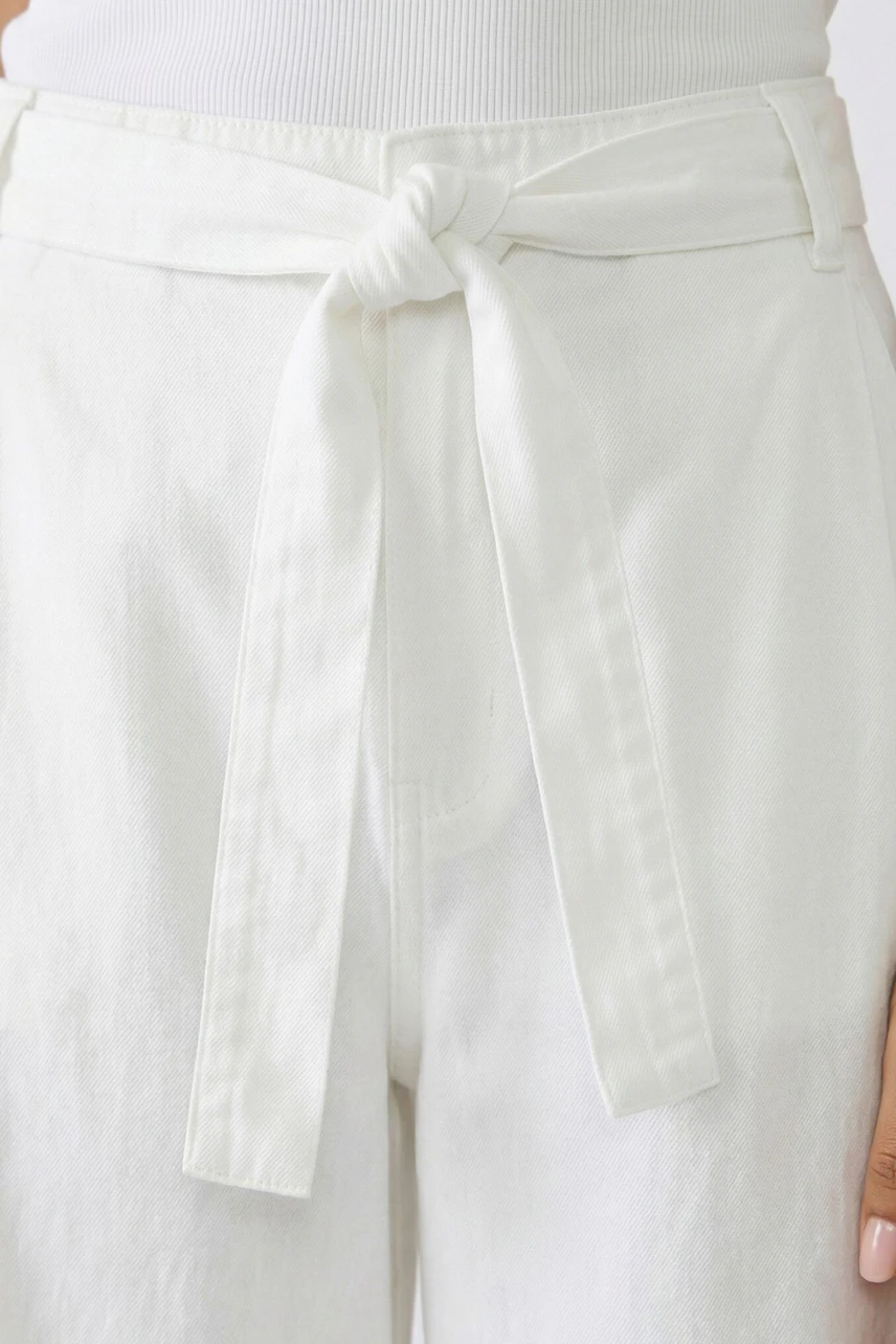 White culotte with tie waist detail, worn by a woman. Casual and stylish for everyday wear.