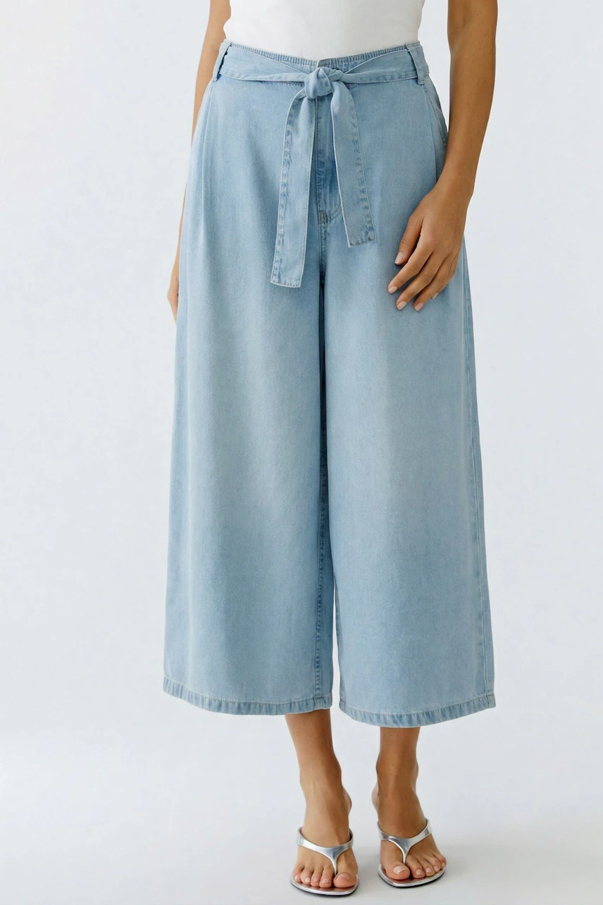 Casual culotte: Woman in light blue wide-leg culotte with tie waist, paired with sandals.