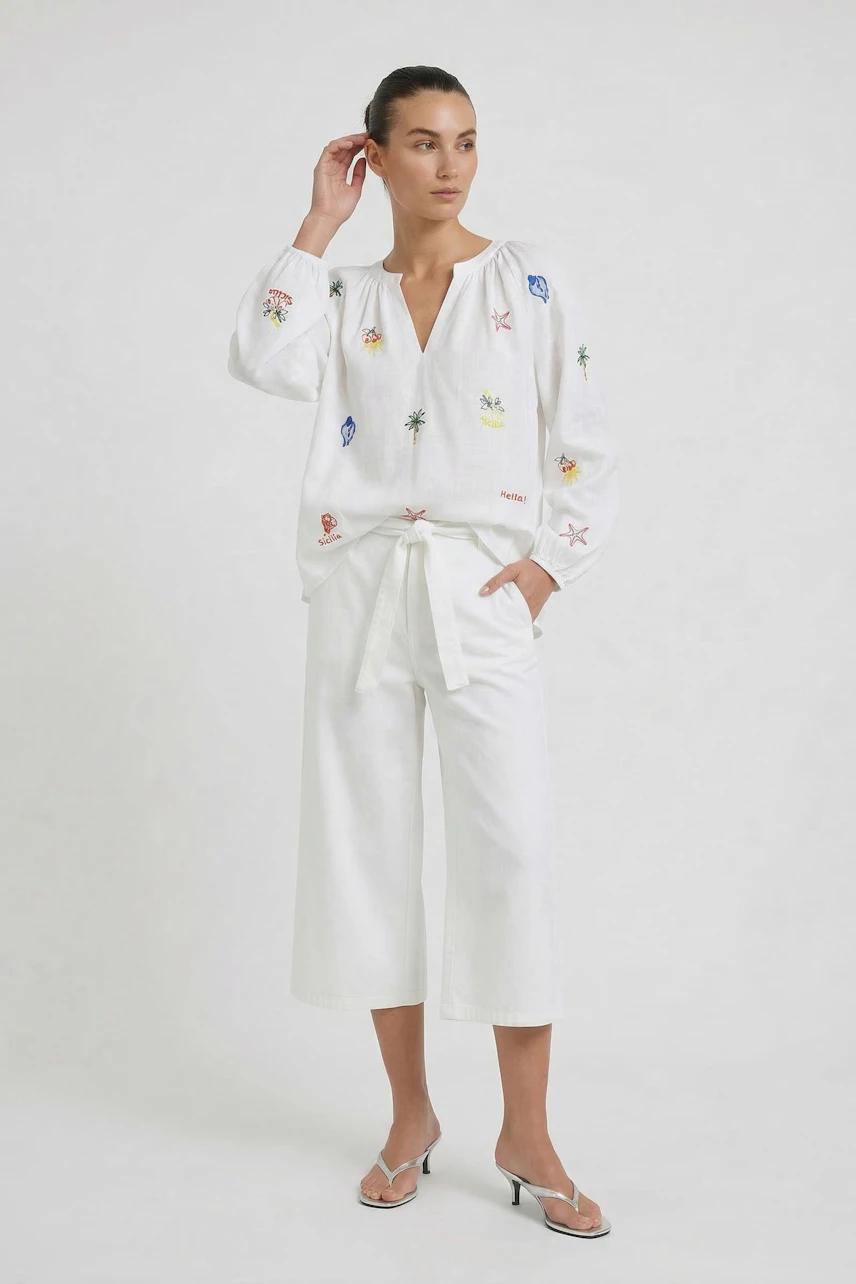 Casual tunic: Woman in a white tunic with colorful embroidery, paired with white pants and sandals.