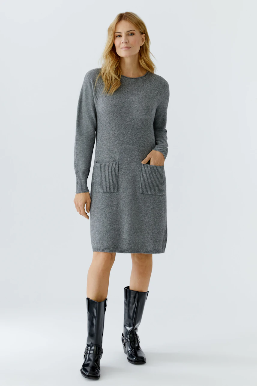 Casual women's knitted dress: A woman in a gray knitted dress with pockets, paired with stylish black boots.